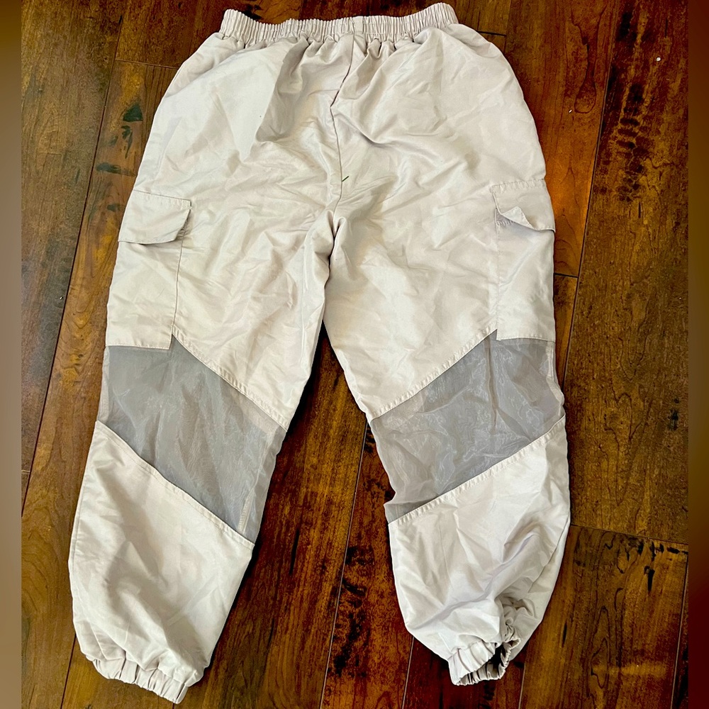 Beige cargo pants with see through knees. Elastic waistband and ankle cuffs
